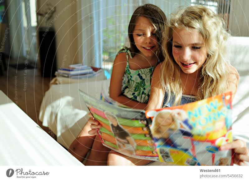 Two girls reading teen magazine females magazines female friends smiling smile child children kid kids people persons human being humans human beings journal