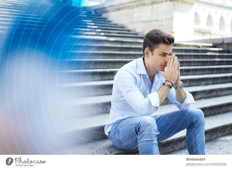Pensive young man sitting on stairs men males Adults grown-ups grownups adult people persons human being humans human beings steps Seated pensive thoughtful