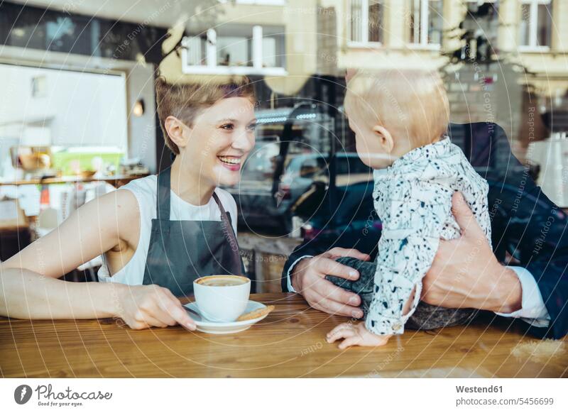 Waitress serving coffee to smiling customer with baby in cafe portrait portraits smile Coffee waitress waitresses Businessman Business man Businessmen