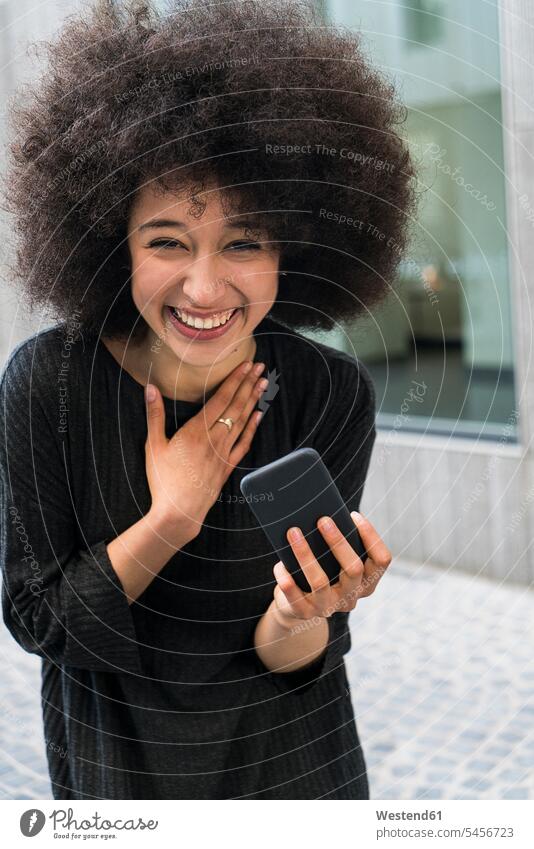 Portrait of laughing young woman with smartphone females women portrait portraits Laughter Adults grown-ups grownups adult people persons human being humans