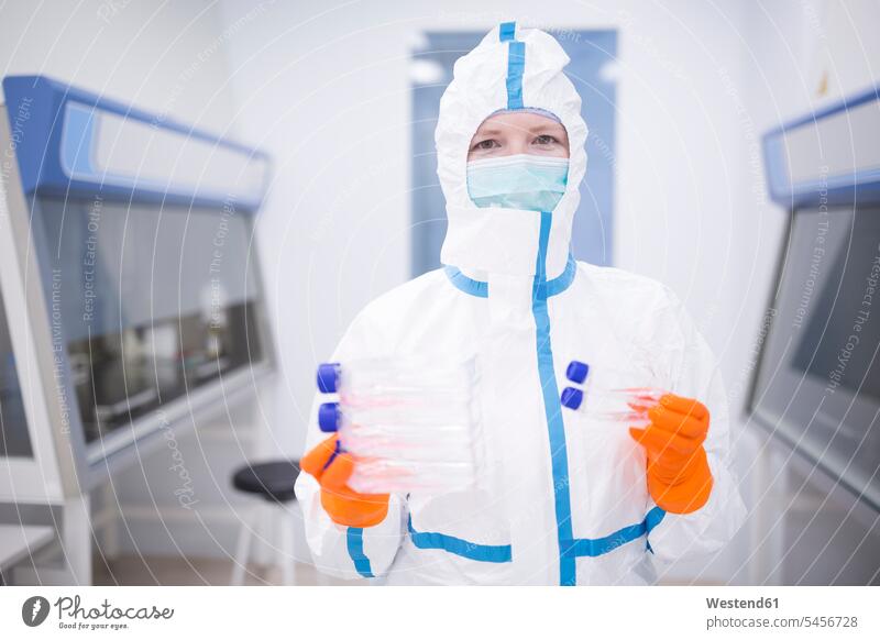 Lab technician wearing cleanroom overall holding cultivation containers laboratory scientist working At Work science sciences scientific laboratory technician