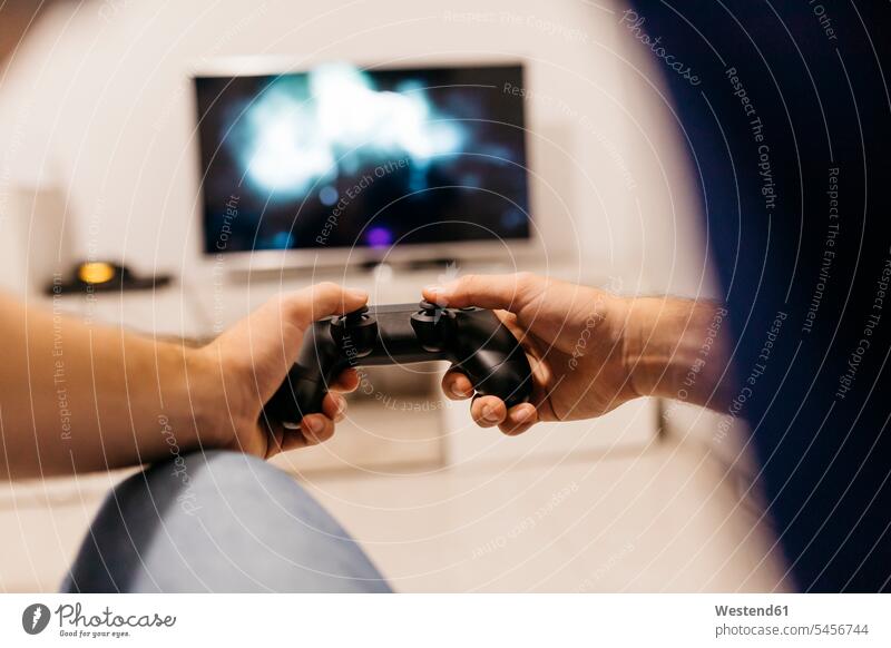 Hands of young male gamer holding controller while playing at home color image colour image indoors indoor shot indoor shots interior interior view Interiors