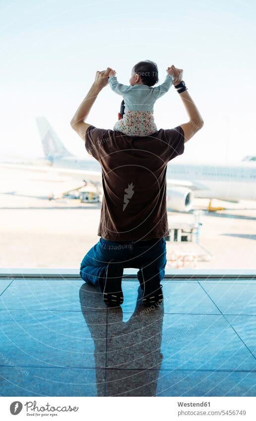 Man carrying a baby girl on his shoulders at the airport and looking at the airplanes, rear view sitting Seated Wanderlust Itchy Feet window windows terminal