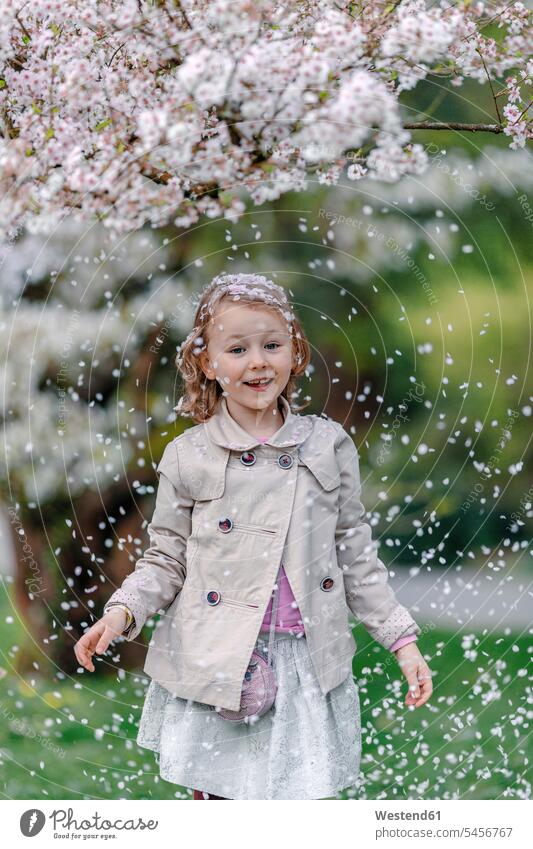 Portrait of happy little girl in a park standing under blossoming Japanese cherry tree human human being human beings humans person persons caucasian appearance