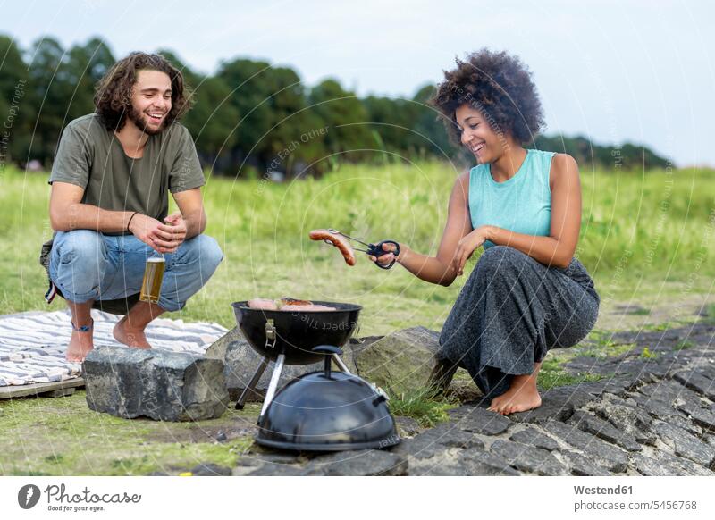 Happy couple having a barbecue in the nature natural world Barbecue BBQ Barbeque twosomes partnership couples happiness happy people persons human being humans