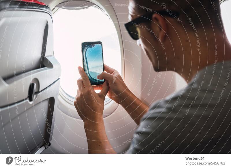 Man in airplane, using smartphone, taking a picture, airplane window Smartphone iPhone Smartphones Traveller Travellers Travelers photographing use man men