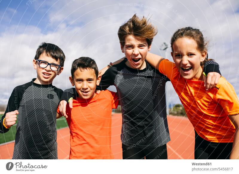 Friends in a sports team standing on running track, with arms around, shouting human human being human beings humans person persons child kid kids 8 to 9