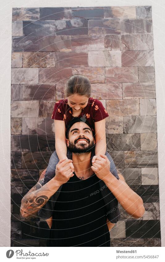 Father carrying daughter on shoulder while standing against wall color image colour image outdoors location shots outdoor shot outdoor shots day daylight shot