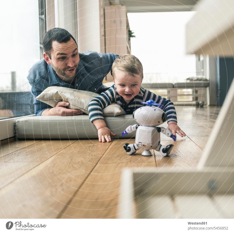 Excited father and son lying on a mattress at home watching a toy robot laying down lie lying down excitement Exciting pa fathers daddy dads papa Mattress