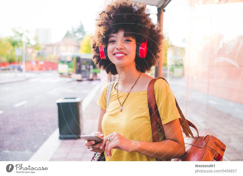 Happy young woman with afro hairdo listening to music with headphones in the city human human being human beings humans person persons curl curled curls
