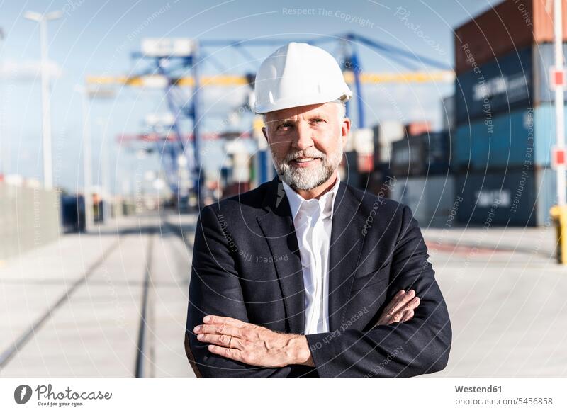 Businessman at cargo harbour, wearing safety helmet, arms crossed entrepreneur entrepreneurs enterpriser Cargo harbour cargo harbors Cargo harbours Success