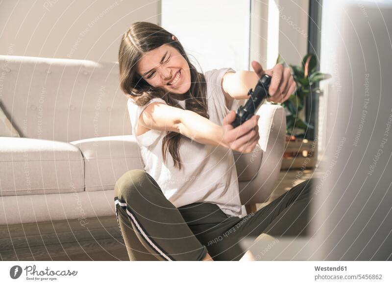 Happy young woman playing video game at home Germany video games games console game console Game Consol paddle computer game computer games flat flats apartment