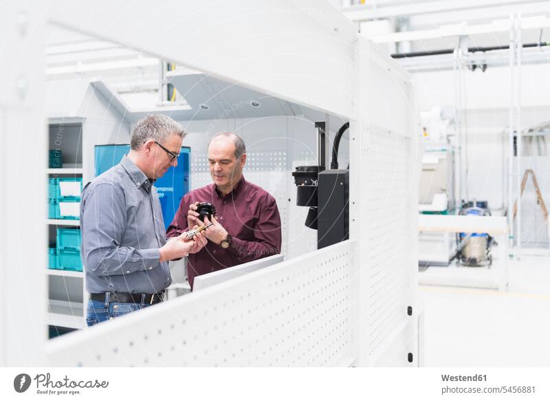 Two businessmen examining product in a factory Occupation Work job jobs profession professional occupation stand clerk clerks employees indoor indoor shot