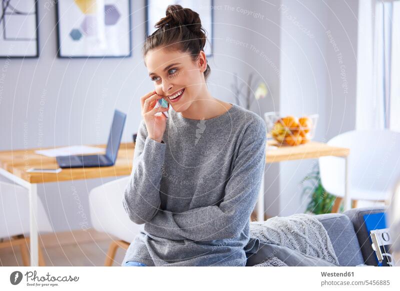 Young woman sitting at home, talking on the phone caucasian caucasian ethnicity caucasian appearance european Internet The Internet laptop Laptop Computers