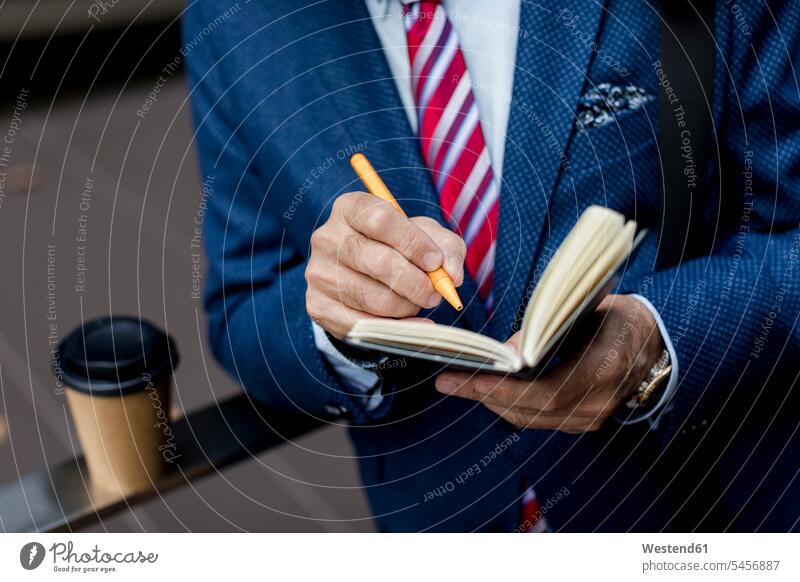 Close-up of businessman writing in diary outdoors write Businessman Business man Businessmen Business men personal organizer date book datebook day planner