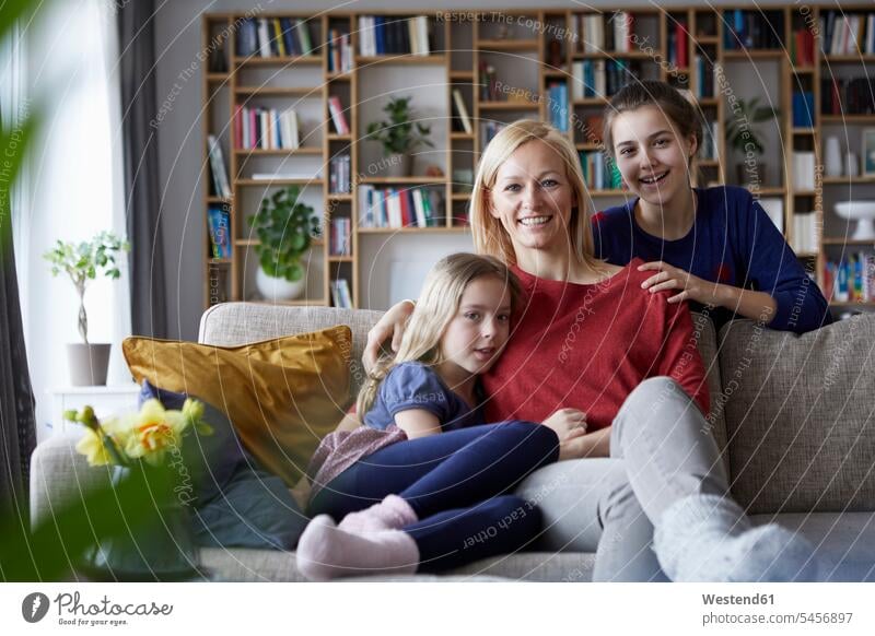 Mother and her daughters cuddling and having fun, sitting on couch mother mommy mothers ma mummy mama parents family families people persons human being humans