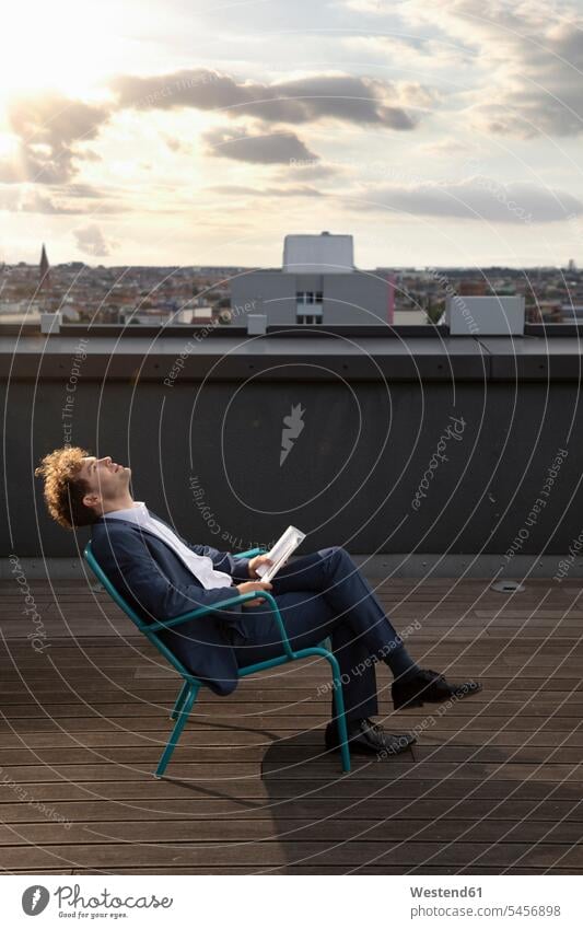Germany, Berlin, businessman relaxing on roof terrace at sunset Businessman Business man Businessmen Business men deck rooftop sunsets sundown relaxation