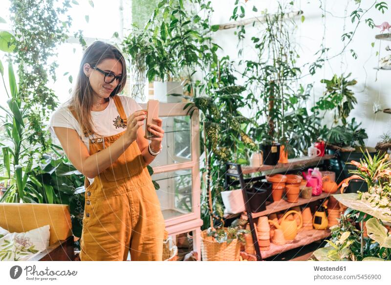 Young woman taking smartphone picture in a small gardening shop Occupation Work job jobs profession professional occupation images pictures photo photographs