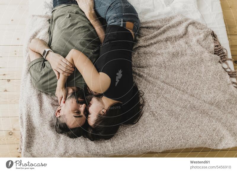 Couple lying on bed, kissing, cuddling and embracing beds home at home couple twosomes partnership couples embrace Embracement hug hugging kisses snuggle cuddle