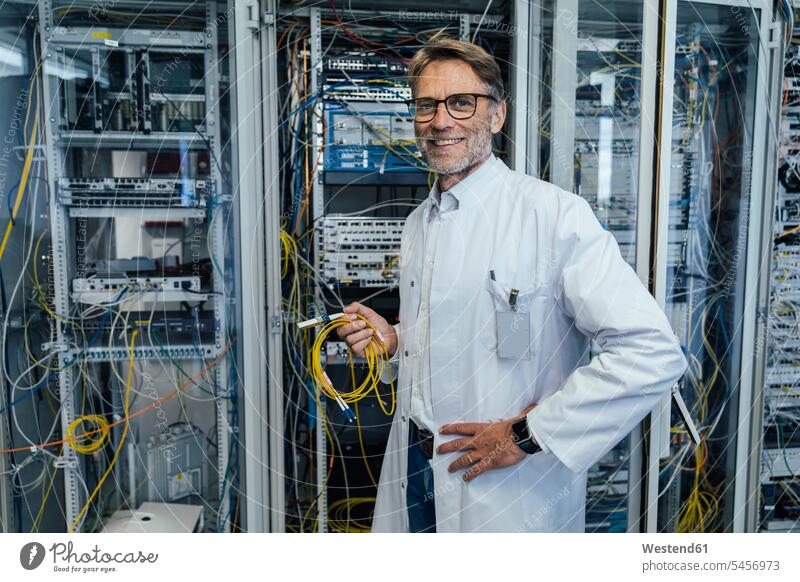 Male IT professional holding cables while standing in data center color image colour image indoors indoor shot indoor shots interior interior view Interiors