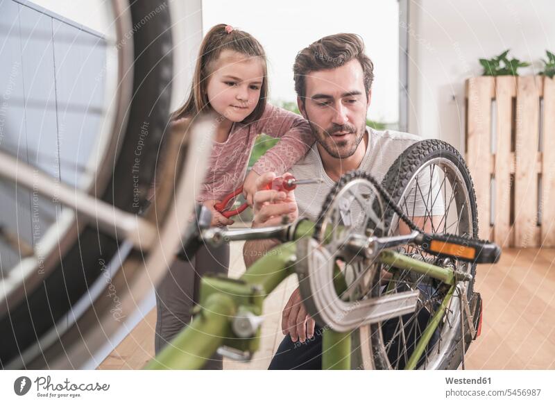 Young man and little girl repairing bicycle together Germany Single Father Showing show one parent sustainability sustainable pliers grippers screw driver