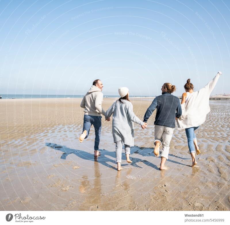 Playful family holding hands while running at beach color image colour image outdoors location shots outdoor shot outdoor shots day daylight shot daylight shots