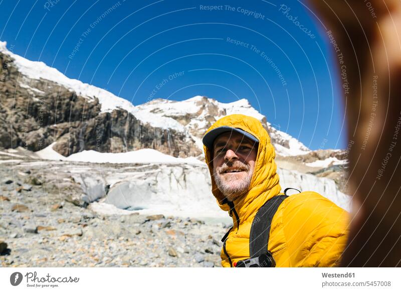 Smiling man taking selfie against snowcapped mountain color image colour image Switzerland Bernina Range mountain range mountains mountain ranges mountain chain