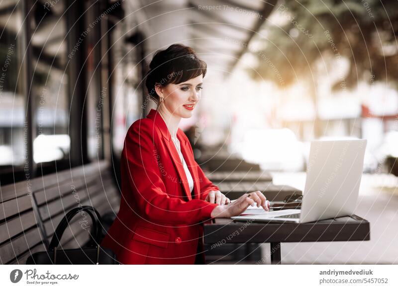 Young confident businesswoman using laptop computer working outdoors, having video call with clients or coworkers sitting at cafe terrace. Successful business. Online meeting, video conference concept