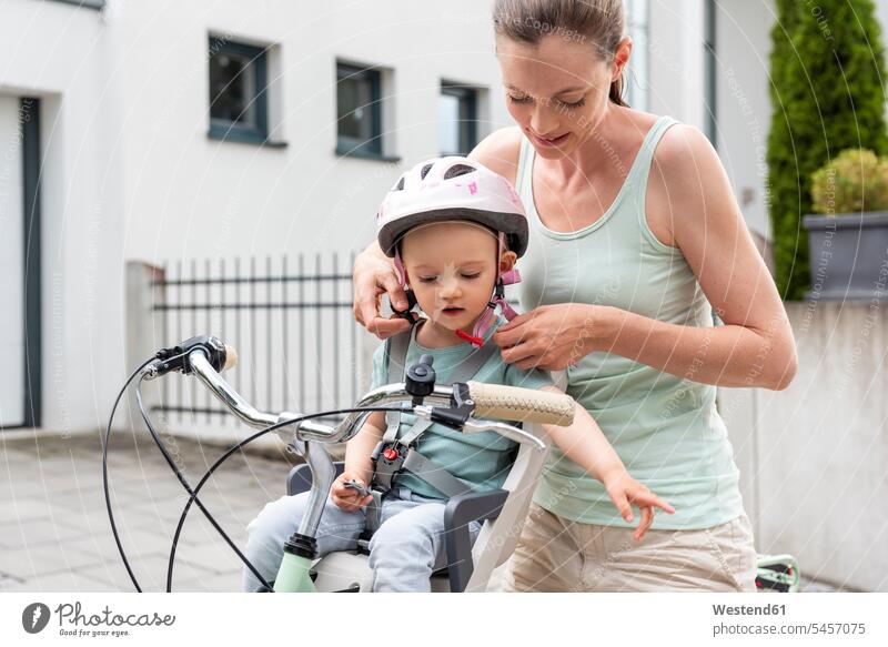 Mother and daughter, daughter wearing helmet sitting in children's seat bicycle bikes bicycles Child's Seat child seat child safety seat mother mommy mothers ma