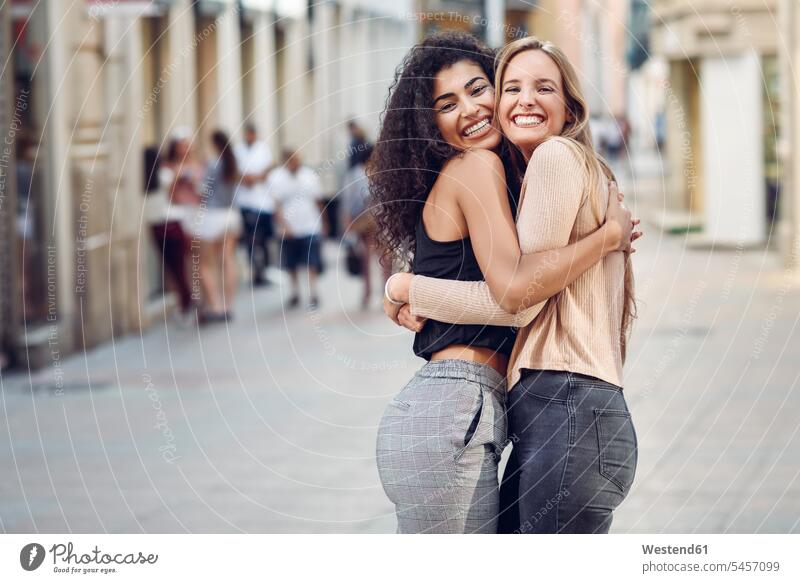 Portrait of two happy friends hugging each other on the street female friends happiness portrait portraits embracing embrace Embracement friendship mate