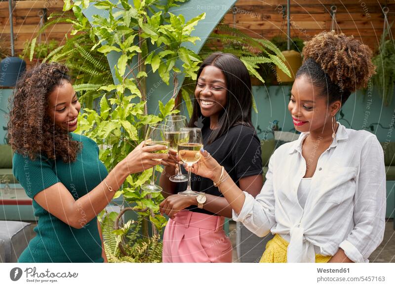 Three happy friends toasting with white wine casual leisure wear casual clothing casual wear casual clothes Casual Attire female friends togetherness bonding
