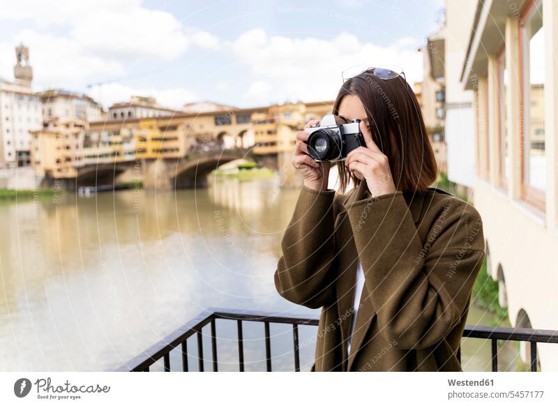 Italy, Florence, young tourist woman taking pictures at Ponte Vecchio Asian Ethnicity Asians River Rivers house houses bridge bridges Arno Architecture landmark