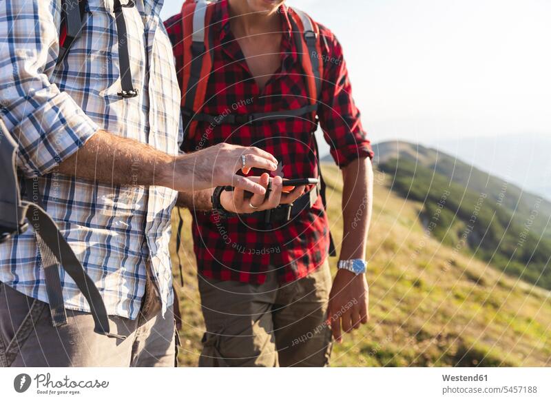 Italy, Monte Nerone, close-up of two men hiking and using smartphone in mountains mobile phone mobiles mobile phones Cellphone cell phone cell phones
