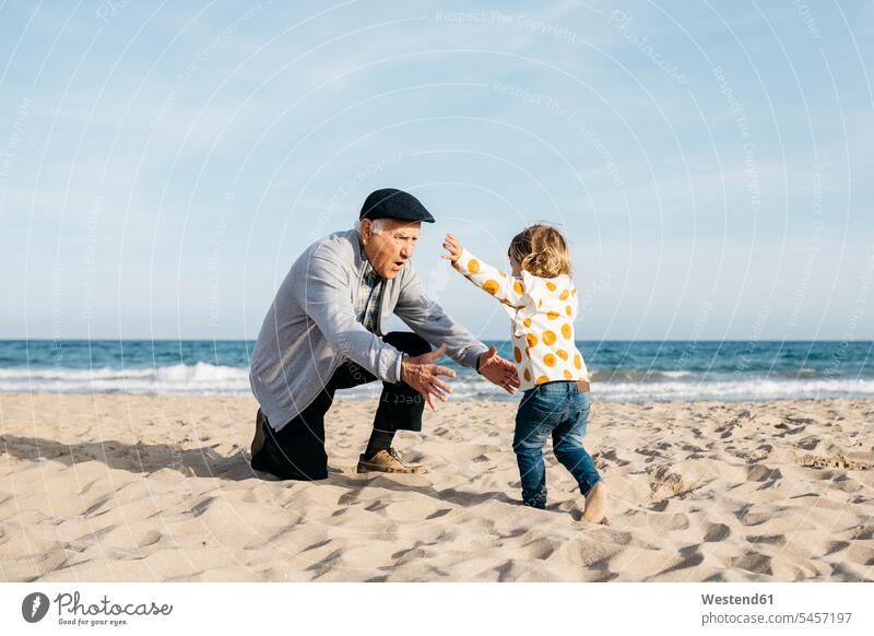 Grandfather playing with his granddaughter on the beach great-grandfather great-grandfathers sandy beach sandy beaches Sea ocean running motion Movement moving