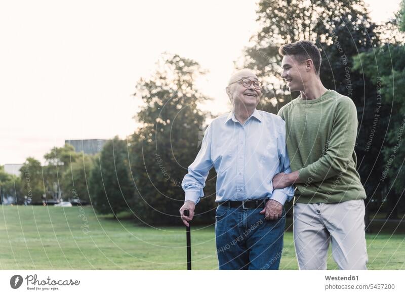 Young man assisting his grandfather walking in a park human human being human beings humans person persons caucasian appearance caucasian ethnicity european 2