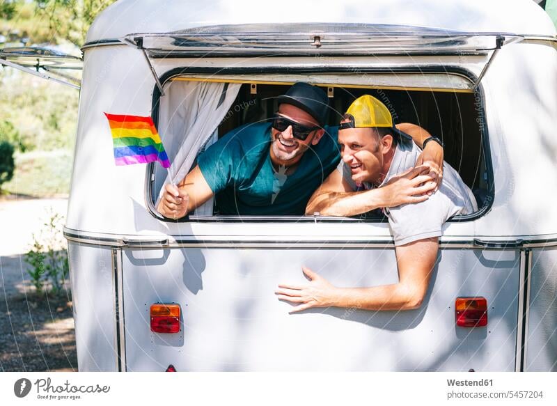 Gay men with rainbow flag enjoying in motor home color image colour image Spain leisure activity leisure activities free time leisure time casual clothing