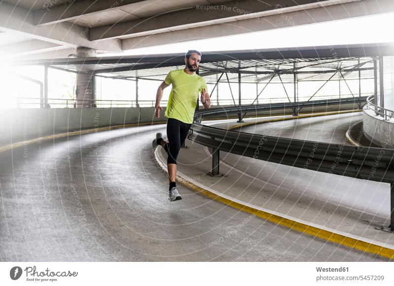 Man running in parking garage in a curve man men males bend curving curved bent turn Curves parking garages parking deck Adults grown-ups grownups adult people