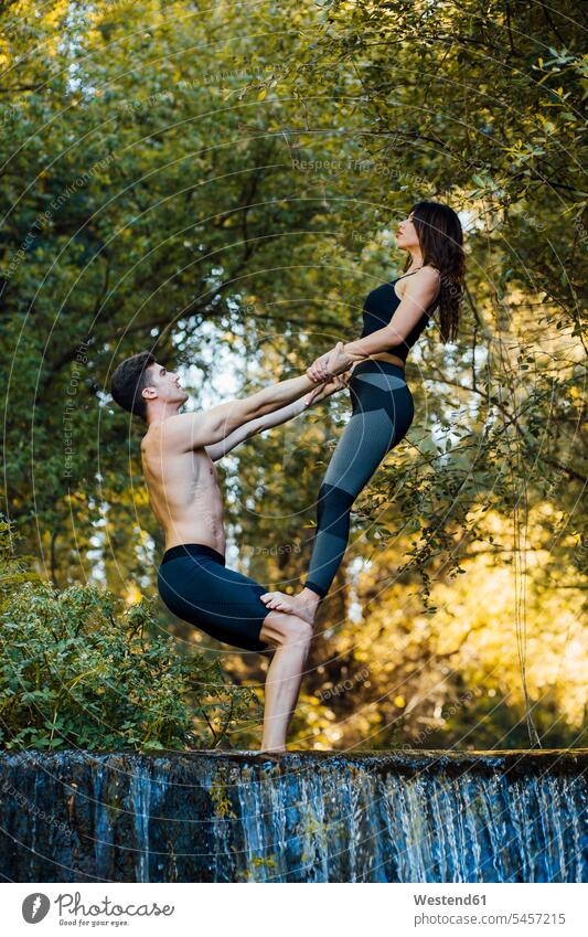 Couple practicing acro yoga together on a waterfall relax relaxing exercise exercising practice practise practising enjoy enjoyment indulgence indulging