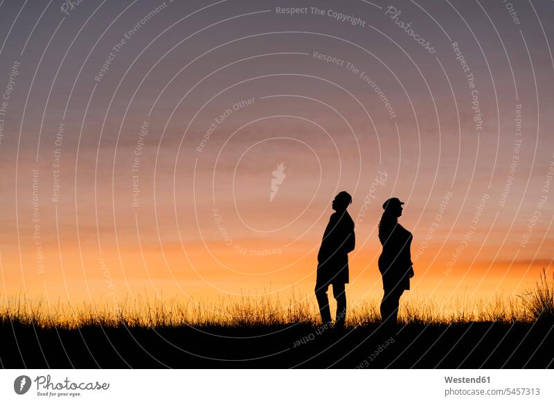 In silhouette of man and woman standing against sky color image colour image outdoors location shots outdoor shot outdoor shots sunset sunsets sundown