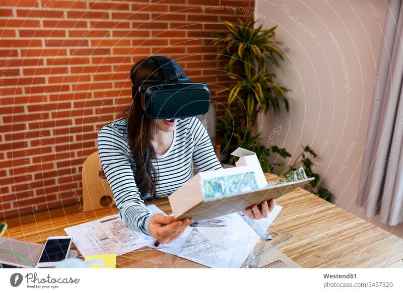 Young woman working in architecture office, looking at model with VR goggles designing sketch female architect architects female architects
