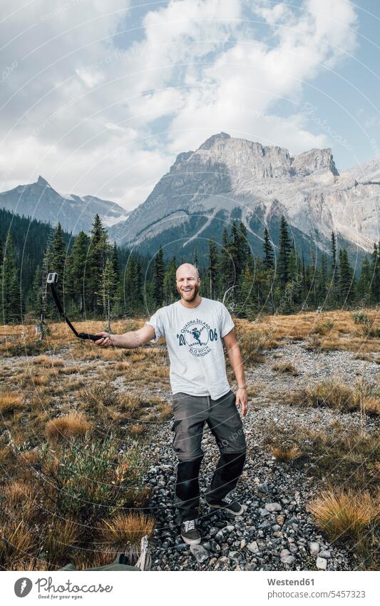 Canada, British Columbia, Yoho National Park, happy man holding selfie stick portrait portraits men males Adults grown-ups grownups adult people persons