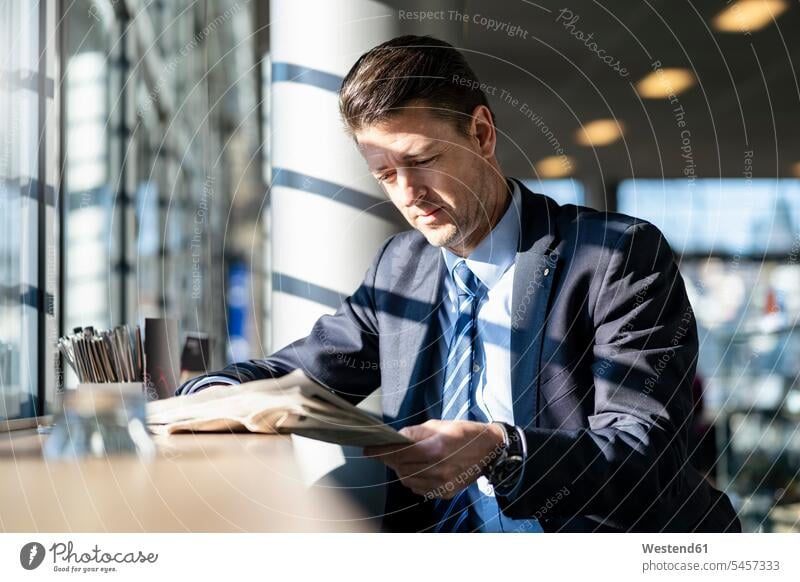 Businessman reading newspaper at the window in a cafe newspapers Business man Businessmen Business men windows business people businesspeople business world