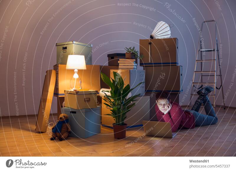 Woman using laptop surrounded by cardboard boxes in a new home human human being human beings humans person persons caucasian appearance caucasian ethnicity