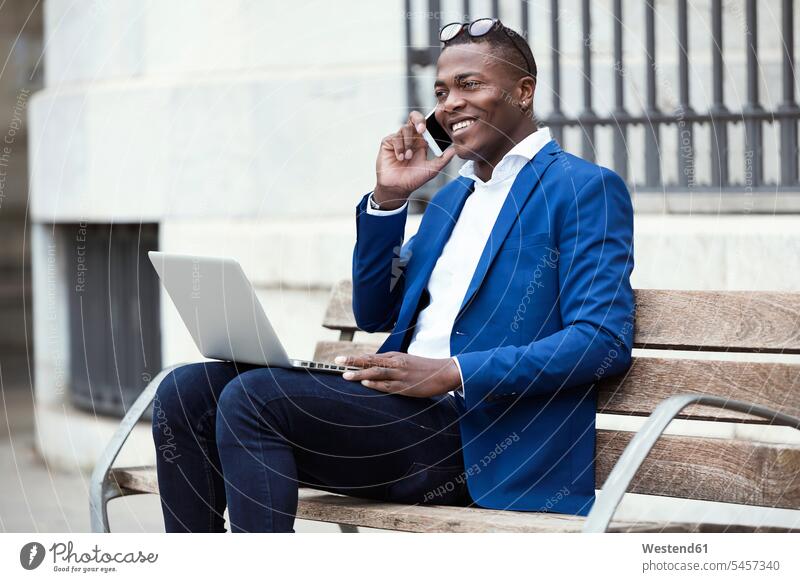 Young businessman wearing blue suit jacket sitting on bench and using smartphone human human being human beings humans person persons African black