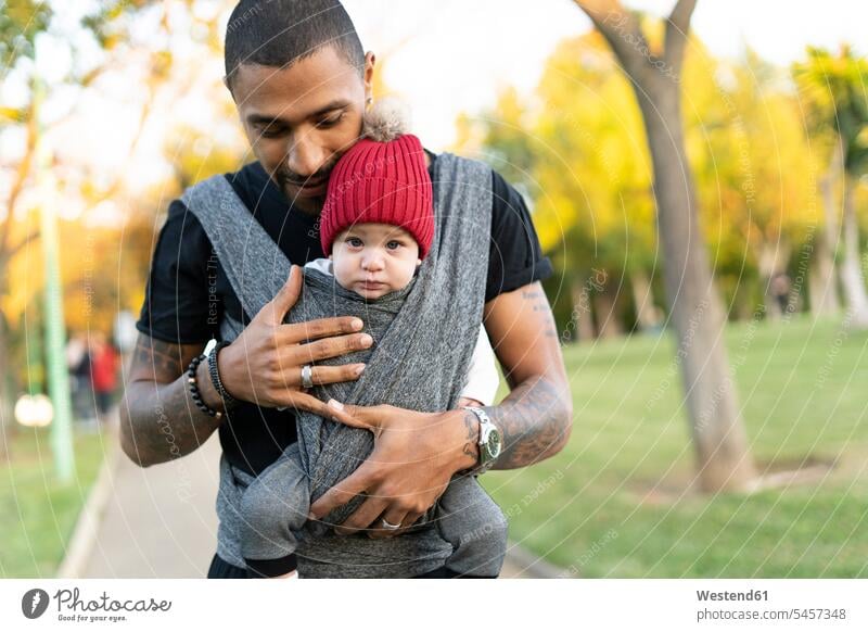 Young father carrying baby son in a baby sling human human being human beings humans person persons Mixed Race mixed race ethnicity mixed-race Person African