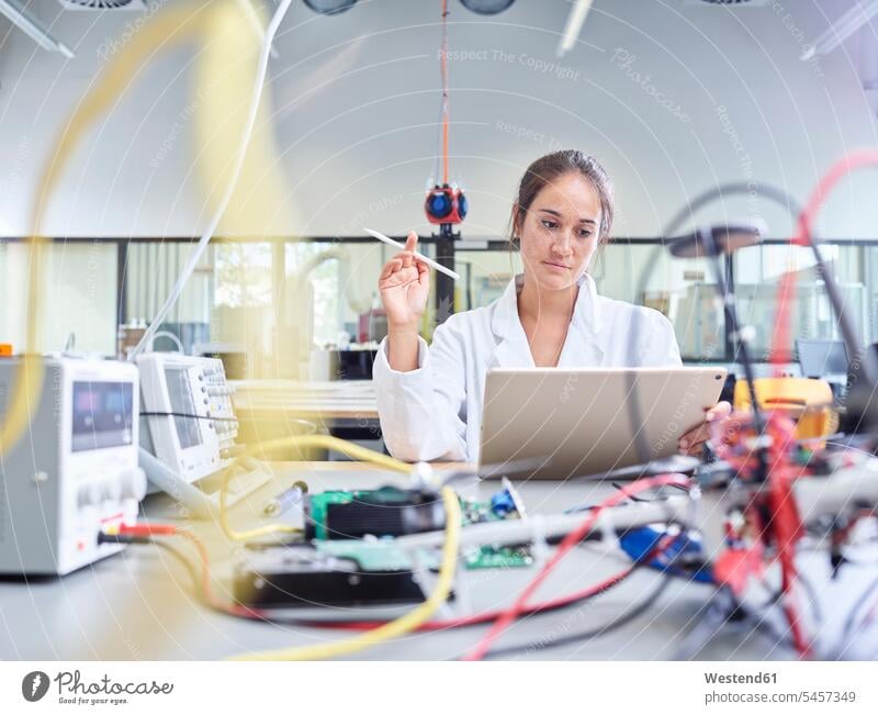 Female technician working in research laboratory, holding pencil in front of tablet occupation profession professional occupation jobs female researcher