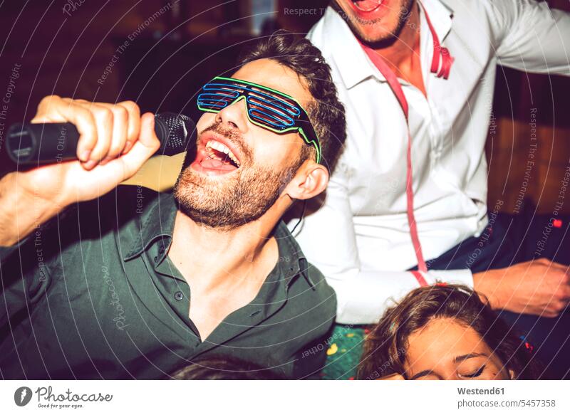 Close-up of young man singing karaoke while enjoying with friends in party color image colour image indoors indoor shot indoor shots interior interior view