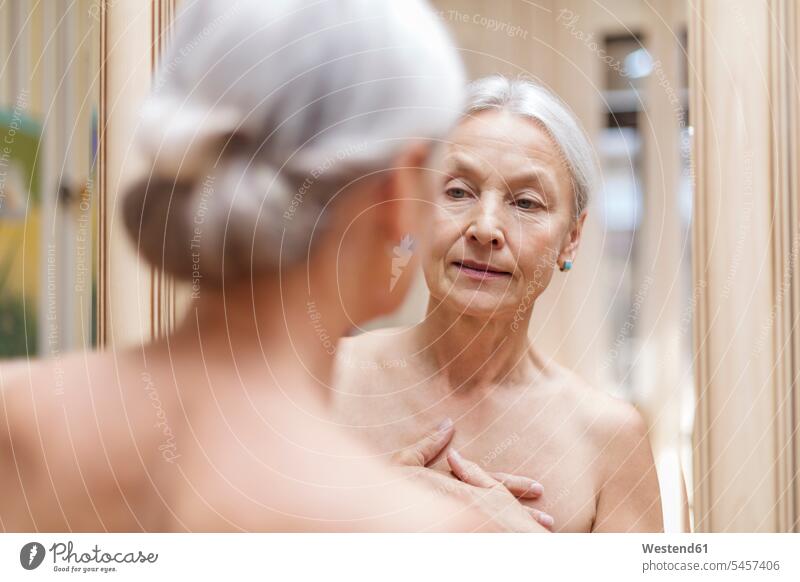 Senior woman looking at her mirror image reflexion reflection senior women elder women elder woman old senior woman females eyeing senior adults Adults