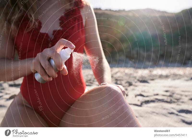 Young woman applying suncream spray on the beach human human being human beings humans person persons caucasian appearance caucasian ethnicity european 1