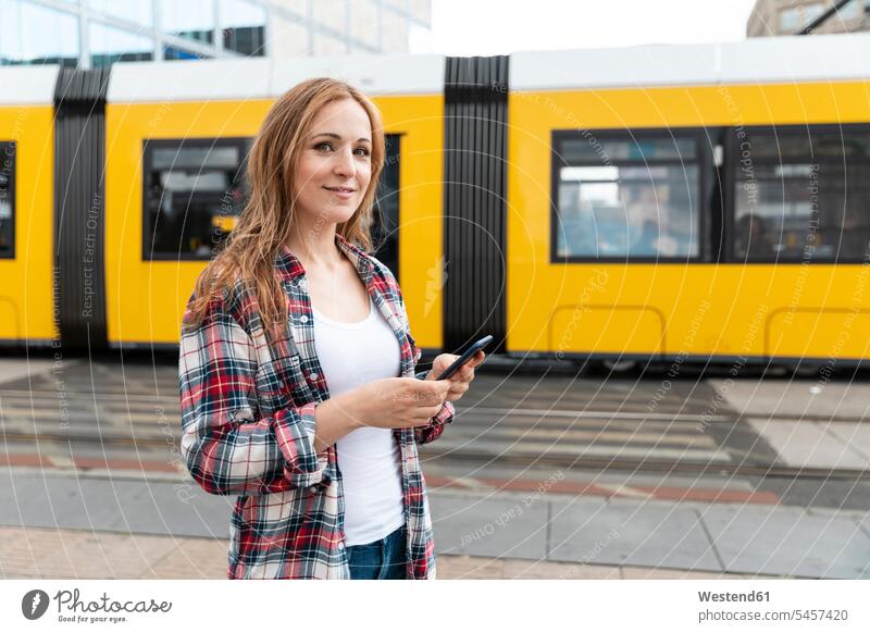 Portrait of a smiling woman in the city with a tram in the background, Berlin, Germany transport railroad railroads Railways streetcar streetcars trams tramways